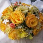 A golden bouquet of Kireo Roses, bronze Dahlias,creamy yellow Lisianthus, coral Spray Roses, coral Hypericum Berries and Stephanotis.
