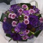This exotic bouquet features deep purple Lisianthis, bi-color lavender Button Mums. lavender Stock, deep purple Artichokes , Purple Hydrangeas, Safari Sunset and Seeded Eucalyptus surrounded by Ti Leaves and Bear Grass.