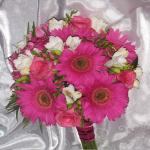 an early summer wedding accented black dresses with these colorful bouquets of shocking pink Gerbera Daisies, fragrant white Freesia and Carousel Roses