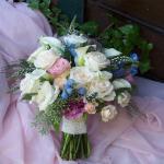 A cluster bouquet of Vendela and Blush  Roses, light blue Bella Donna, White  Lysimachias , pink Lisianthus, Seeded Eucalyptus.
and Mini Ivory Calla Lilies.  
